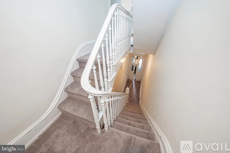 A staircase with a white railing and beige carpet.