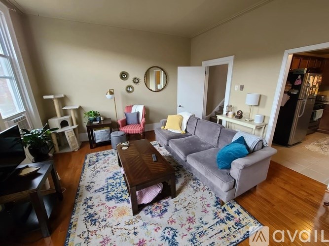 A living room with a grey couch, a wooden coffee table, and a floral rug.