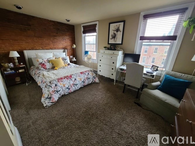 A bedroom with a large bed and a chair.