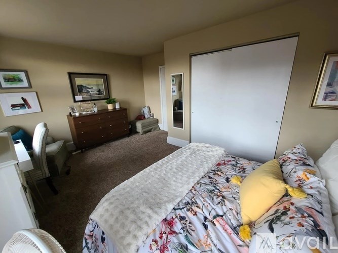 A bedroom with a floral bedspread and a white chair.