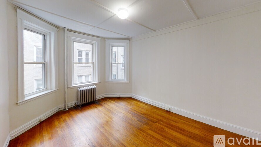 A room with wooden floors and three windows.