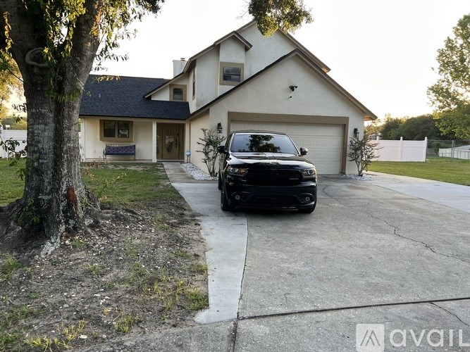 A black SUV is parked in a driveway in front of a two-story house.