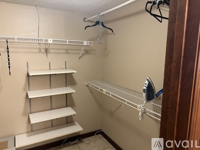 A white shelving unit with a clothes iron on it.