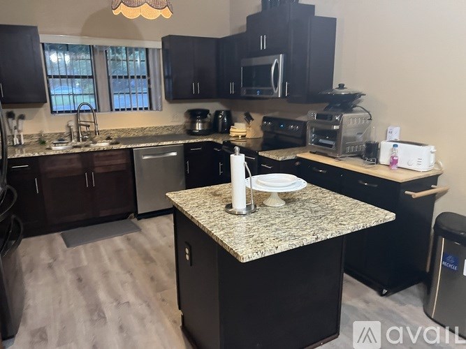 A kitchen with a granite countertop and black cabinets.