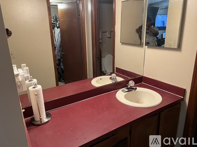 A bathroom with a red countertop and two sinks.