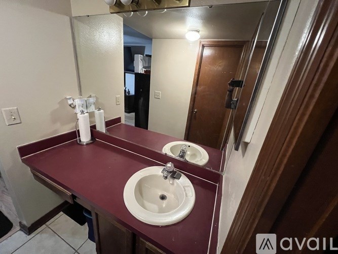 A bathroom with a maroon countertop and two sinks.