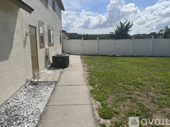A white house with a grey concrete walkway and a white fence.