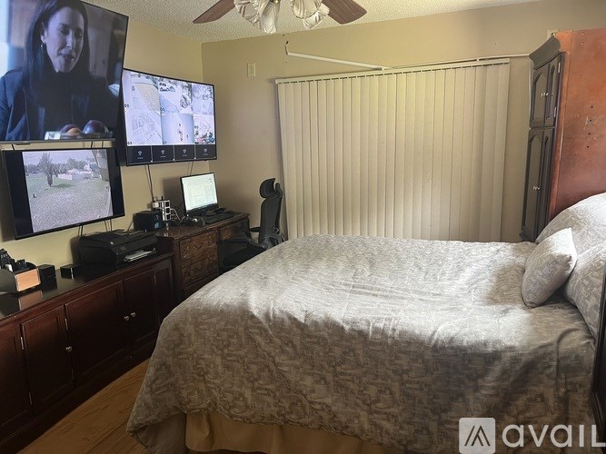 A bedroom with a bed, a ceiling fan, and a television displaying a video call.