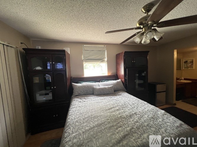 A bedroom with a bed, dresser, and ceiling fan.