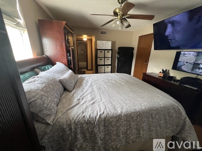 A bedroom with a bed, dresser, and a ceiling fan.