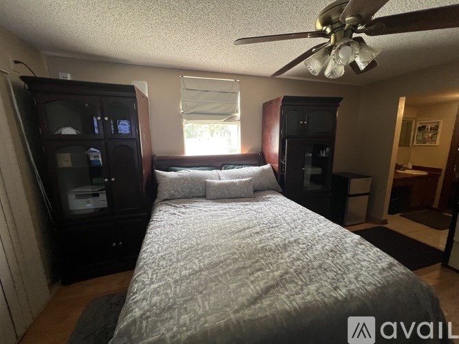 A bedroom with a bed, a ceiling fan, and a microwave.