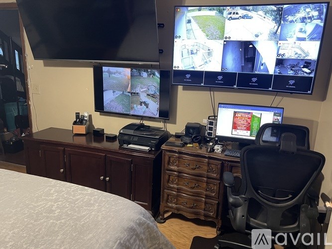 A room with a desk, a chair, and a monitor displaying multiple images.