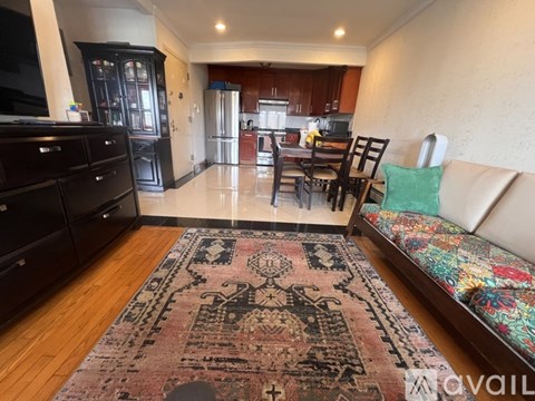 A living room with a rug on the floor and a couch with a green pillow on it.