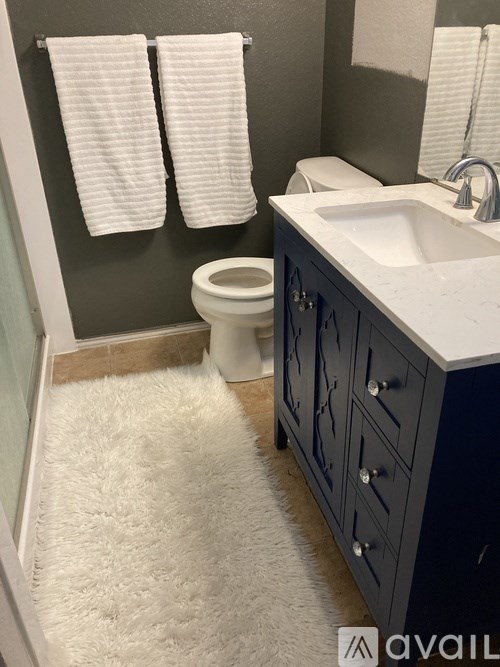 A bathroom with a toilet, sink, and towel rack.