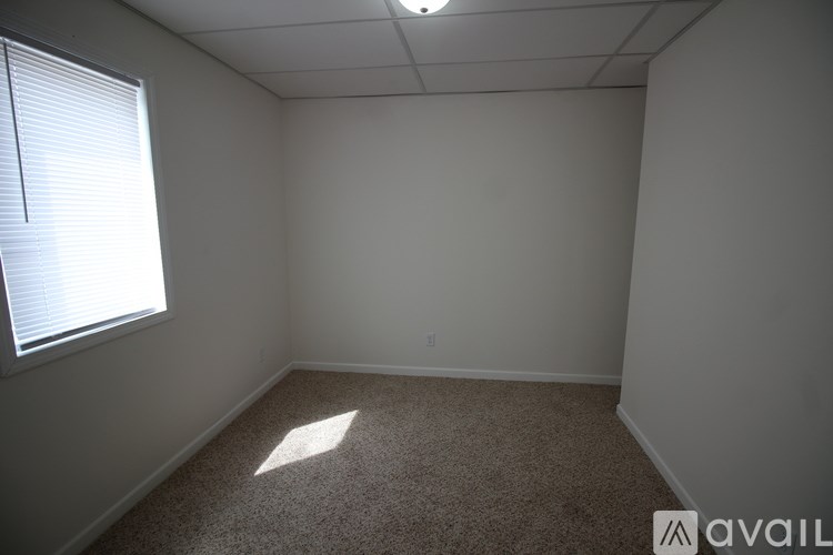 A room with a carpeted floor and a window with blinds.