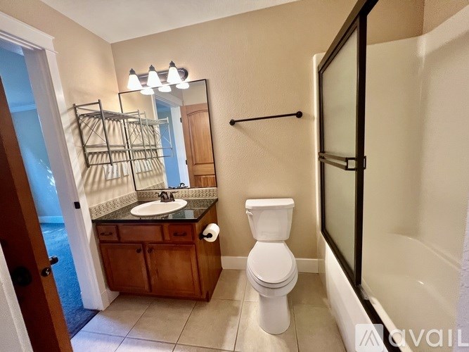 A bathroom with a toilet, sink, mirror, and a walk-in shower.