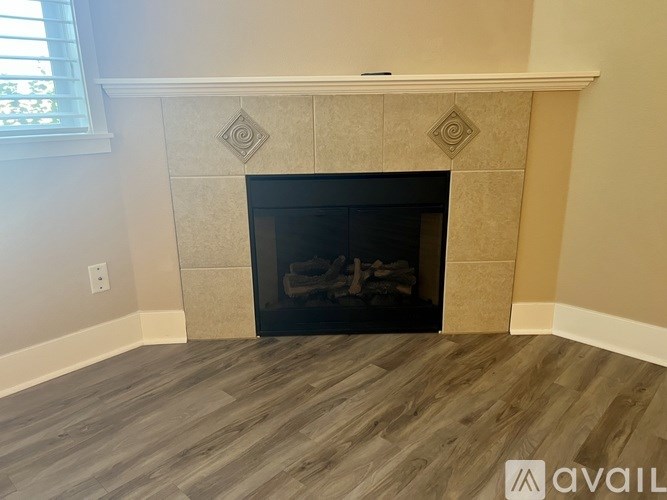 A fireplace with a black screen and a wooden mantle.