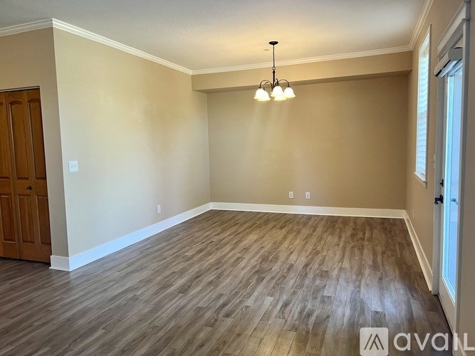 A room with wooden flooring and a chandelier hanging from the ceiling.