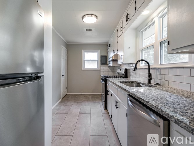 A kitchen with a stainless steel refrigerator and a granite countertop.