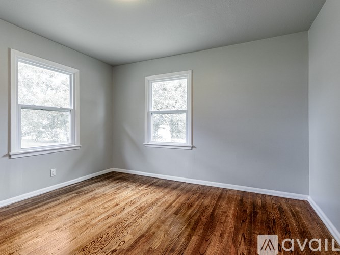 A room with wooden floors and two windows.