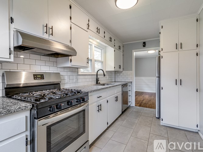 A kitchen with white cabinets and a stainless steel stove top.
