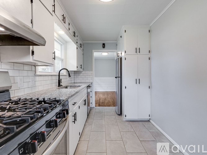 A kitchen with a stove top oven and white cabinets.