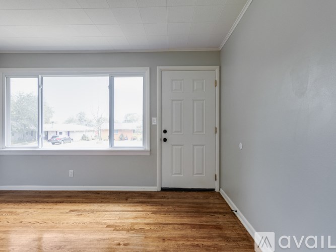 A room with a white door and a window overlooking a parking lot.