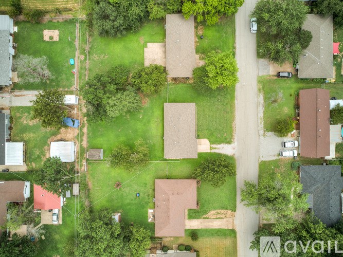 A bird's eye view of a residential area with houses, trees, and a road.