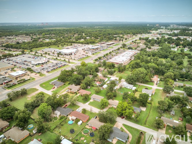 A bird's eye view of a residential area with houses, trees, and a parking lot.