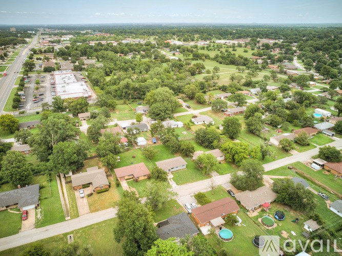 A bird's eye view of a residential neighborhood with houses, trees, and a pool.