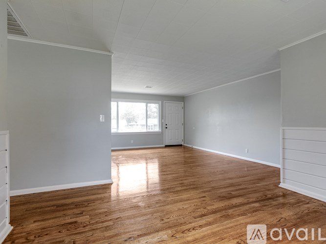 A spacious room with wooden flooring and white walls.