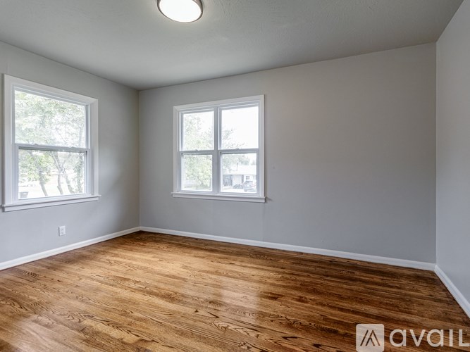 A room with wooden floors and two windows.