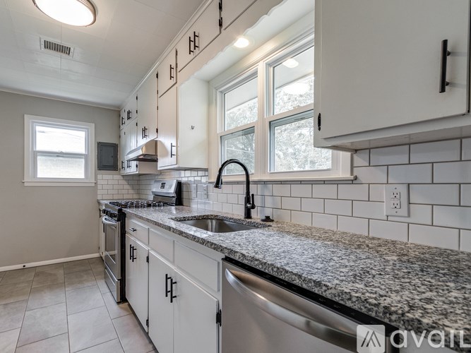 A kitchen with white cabinets and a granite countertop.