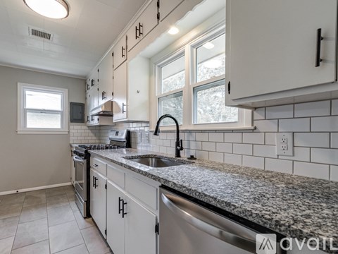 A kitchen with white cabinets and a granite countertop.