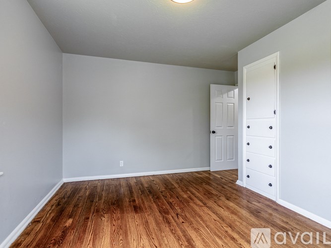 A room with wooden flooring and white walls.