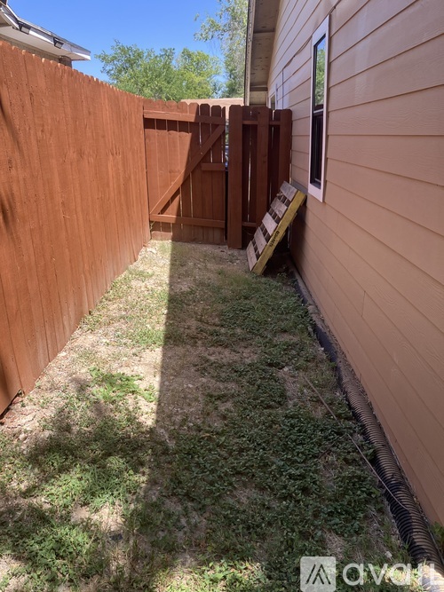 A wooden fence and a small garden area in front of a house.