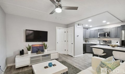A modern living room with a white sofa and a television on the wall.