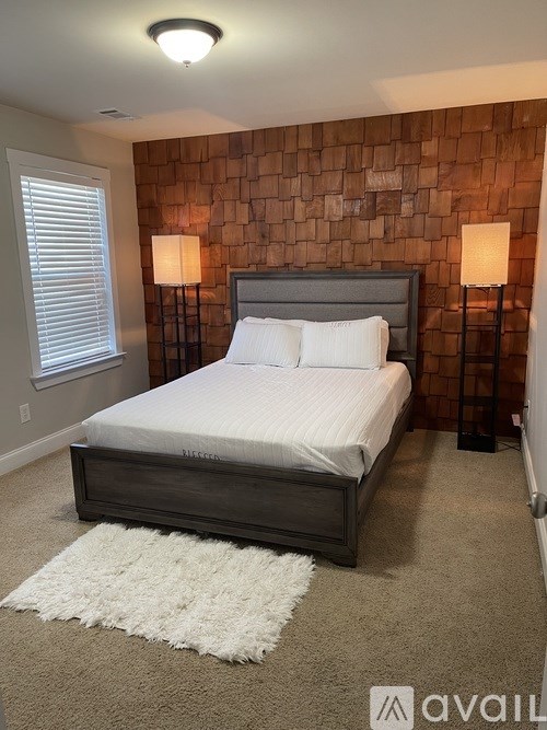 A bedroom with a bed, two lamps, and a rug.