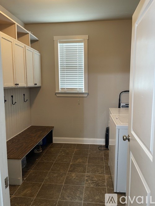 A kitchen with a bench, cabinets, and a window.