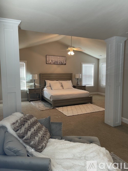 A bedroom with a large bed and a grey couch.