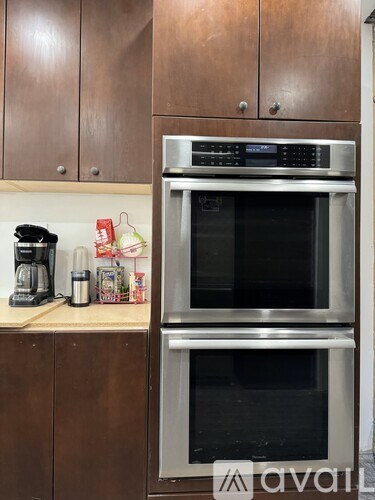 A kitchen with a stainless steel oven built into the cabinetry.