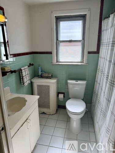 A bathroom with a toilet, sink, and window.