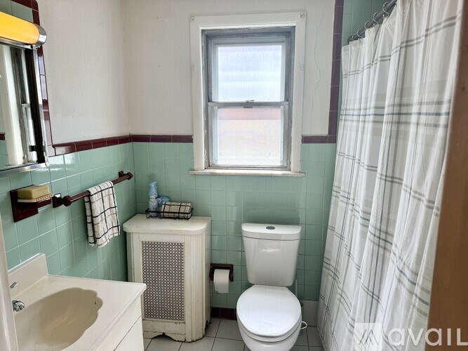 A bathroom with a toilet, sink, and window.