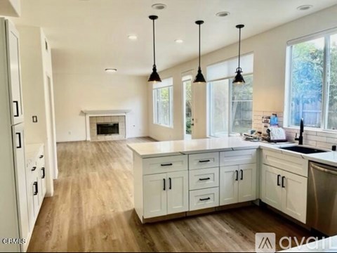A spacious kitchen with white cabinets and a wooden floor.