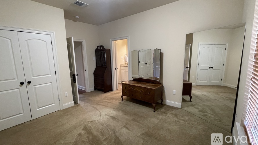 A bedroom with a dresser and mirrors.