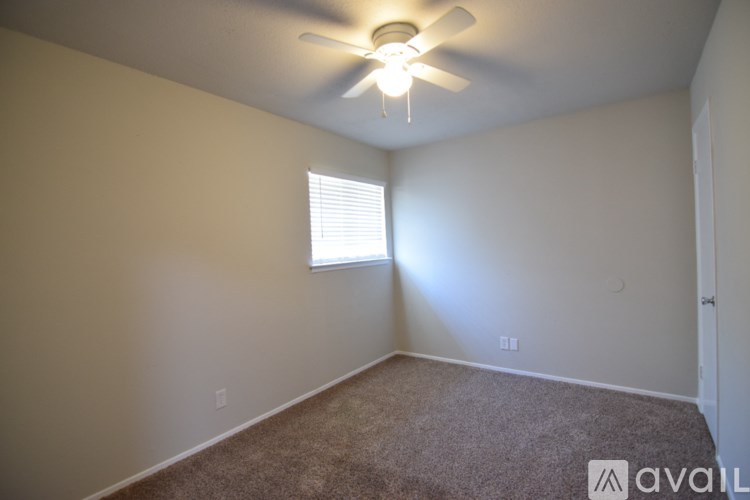 A room with a carpeted floor, a ceiling fan, and a window with blinds.