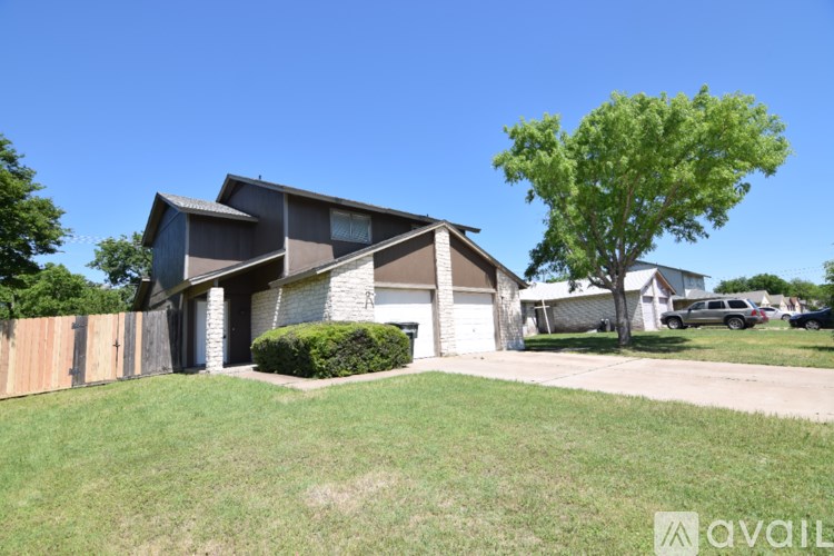 A house with a brown roof and a white garage door is surrounded by a wooden fence.