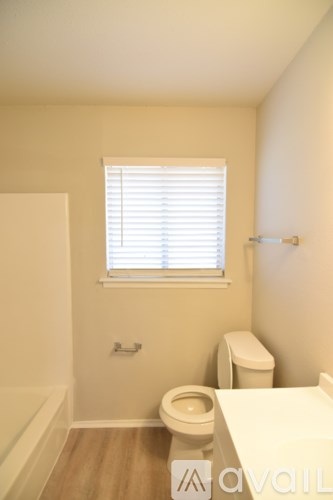 A bathroom with a toilet, sink, and window.
