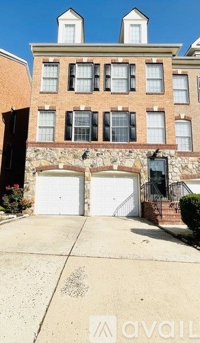 A brick building with a stone wall and two garage doors.