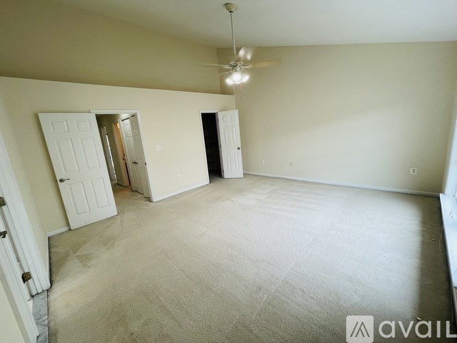 A spacious room with a carpeted floor and a ceiling fan.